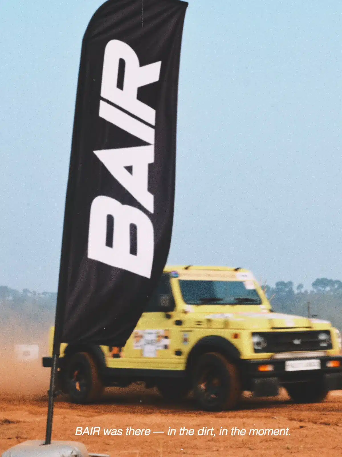 Bair flag flying with a yellow off-road vehicle in the dirt.
